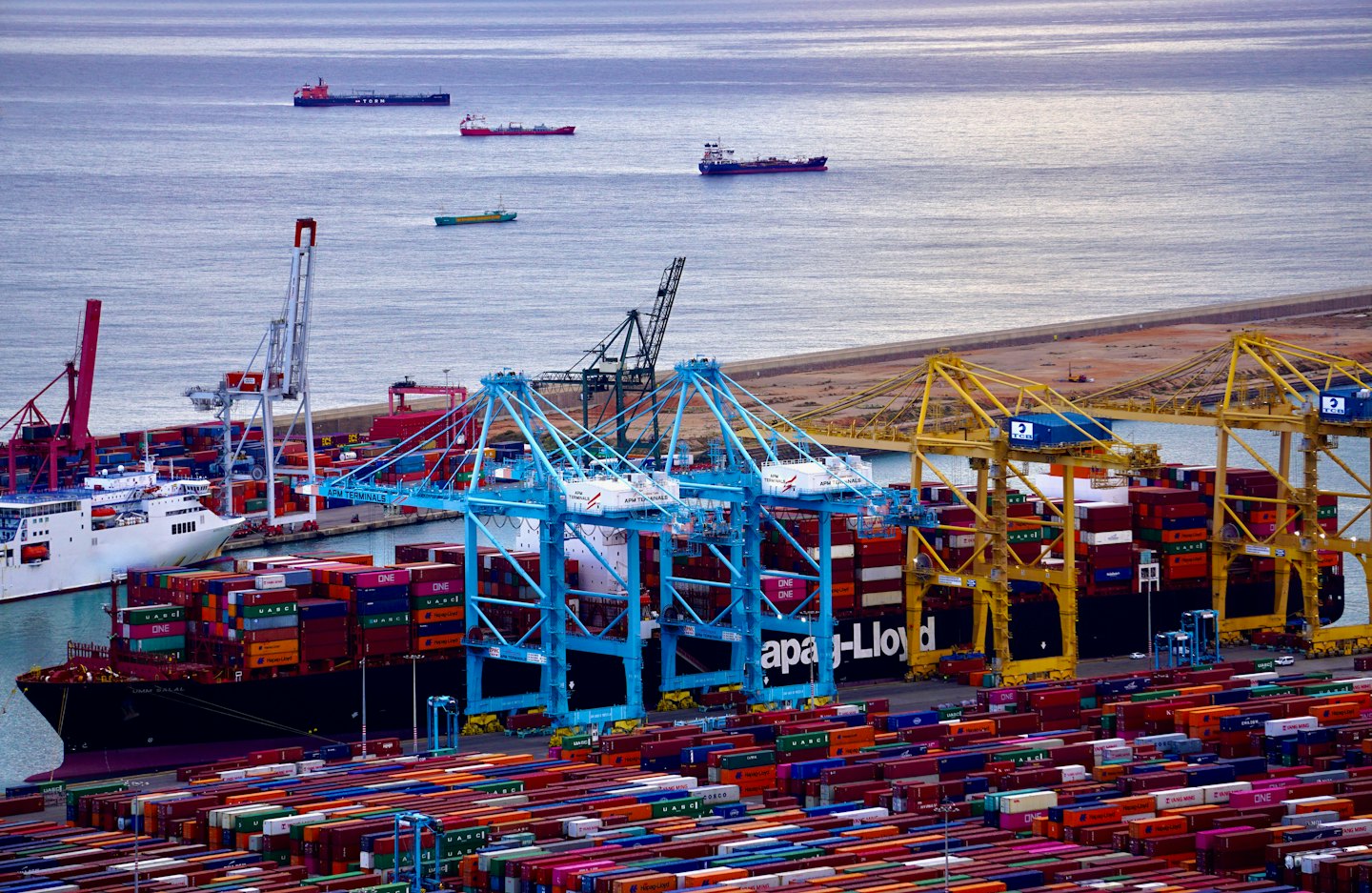 Navi cargo e container in un porto commerciale affollato.